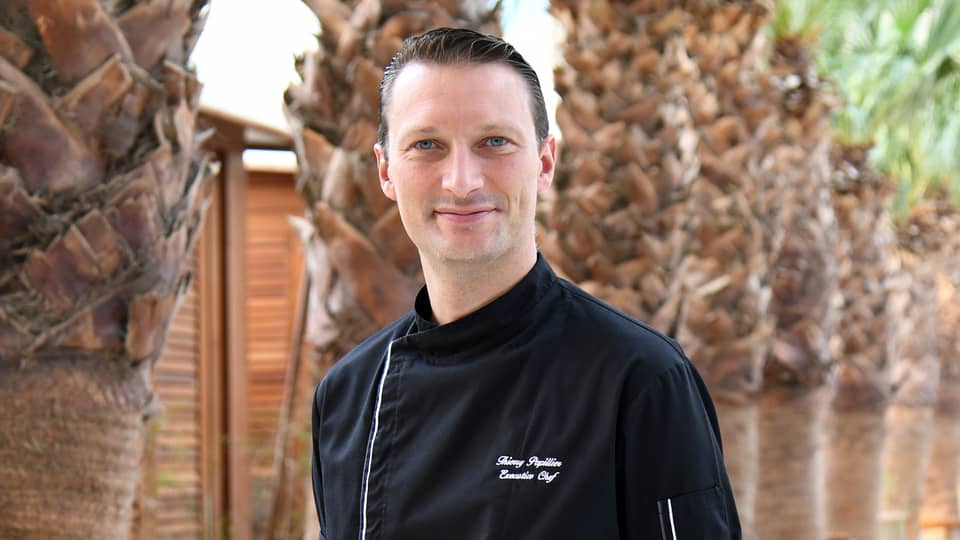 Chef Thierry Pillier stands looking at the camera wearing a black chef's jacket