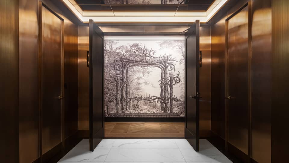 Interior wood-panelled hallway with two doors opening up to reveal a black-and-white painting