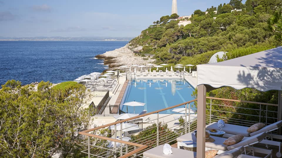 View from terrace of Club Dauphin pool, Mediterranean, green hillside and lighthouse