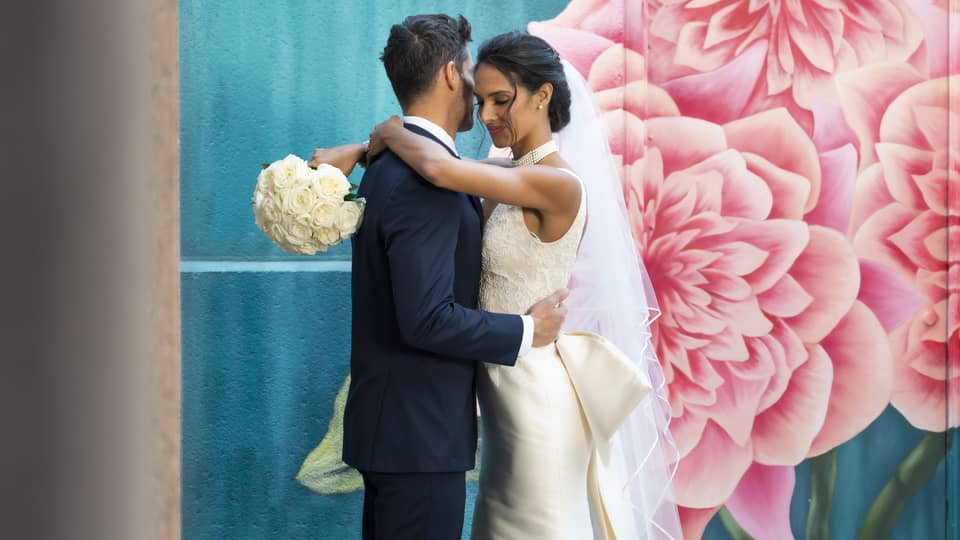 A woman in a wedding dress holding a man in a suit.