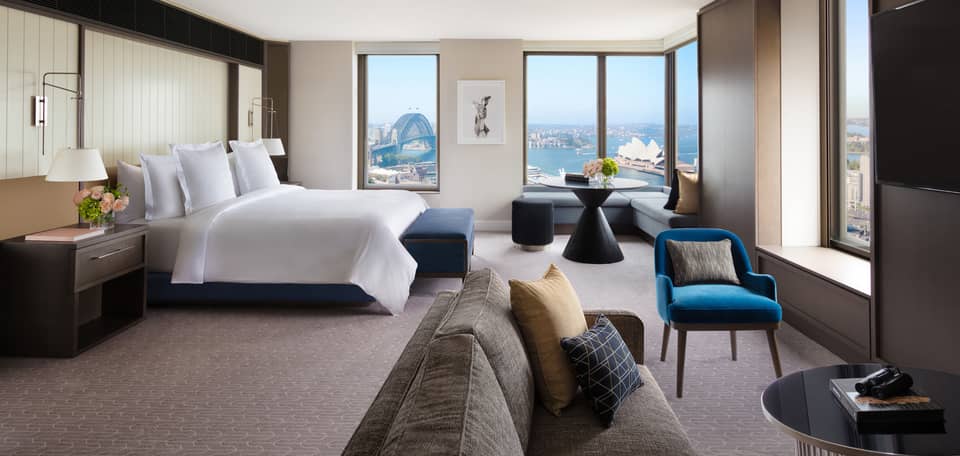 A cozy bedroom with subtle bursts of colourful decor, overlooking the iconic Sydney Harbour