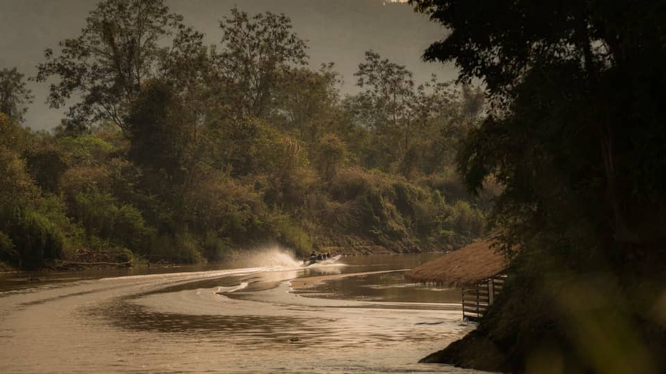 Longtail boat sprays water as it zips down the Ruak river