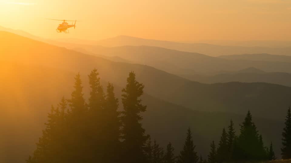 Helicopter at sunset flying over Aspen Mountain in the Elks Mountain range