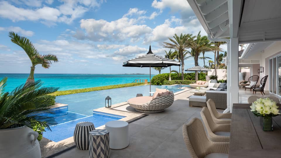 Beachfront villa residence terrace with private infinity pool, sun loungers, and ocean view under a bright blue sky