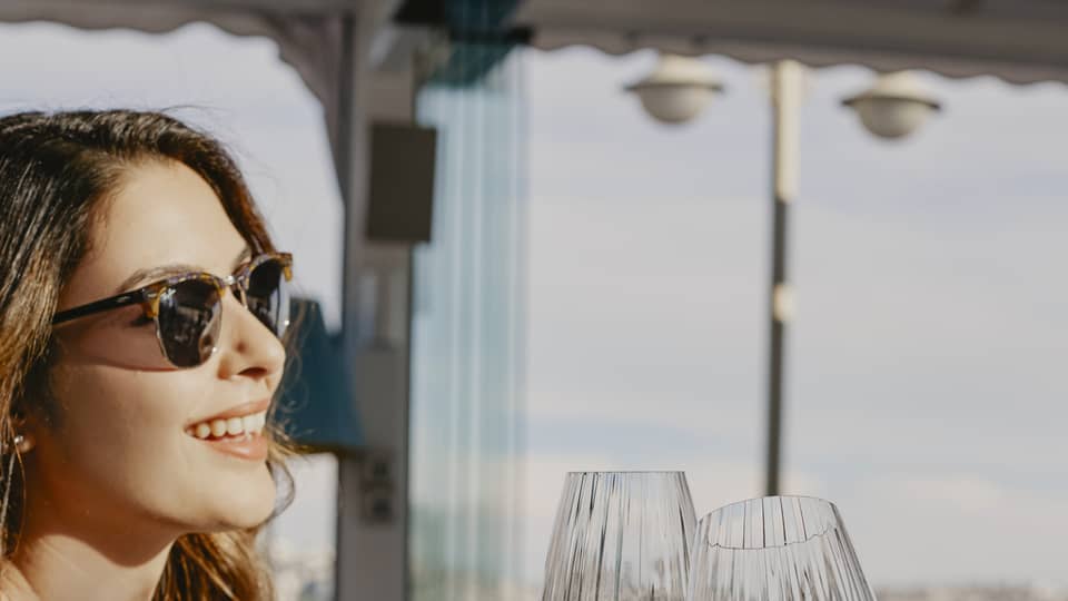 Person sitting at terrace restaurant table, toasting with a glass of wine