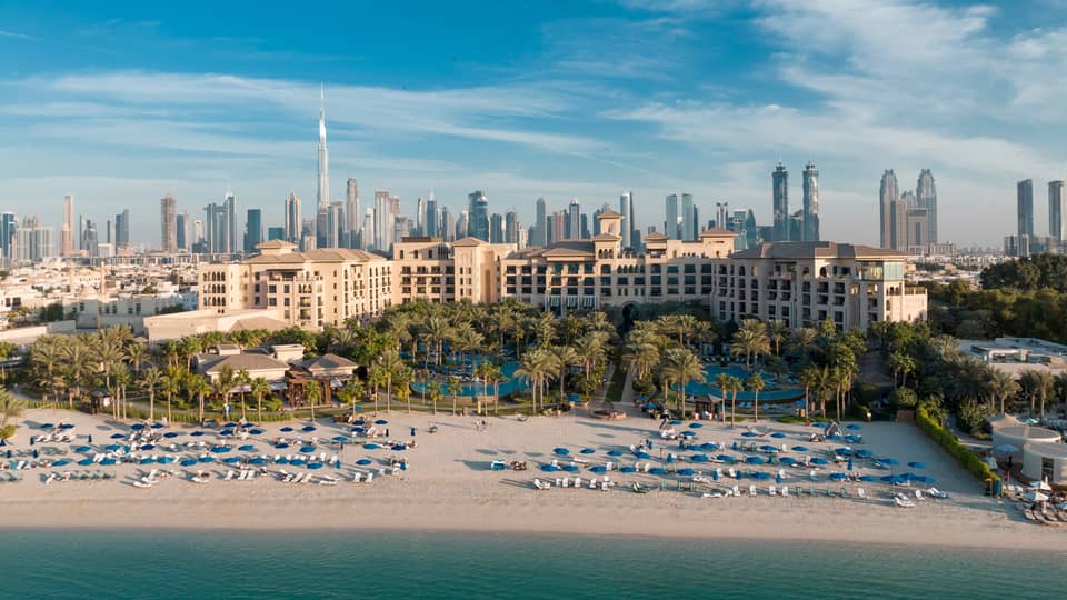 An aerial view of Dubai Jumeirah Beach of the ocean, with the city skyline behind.