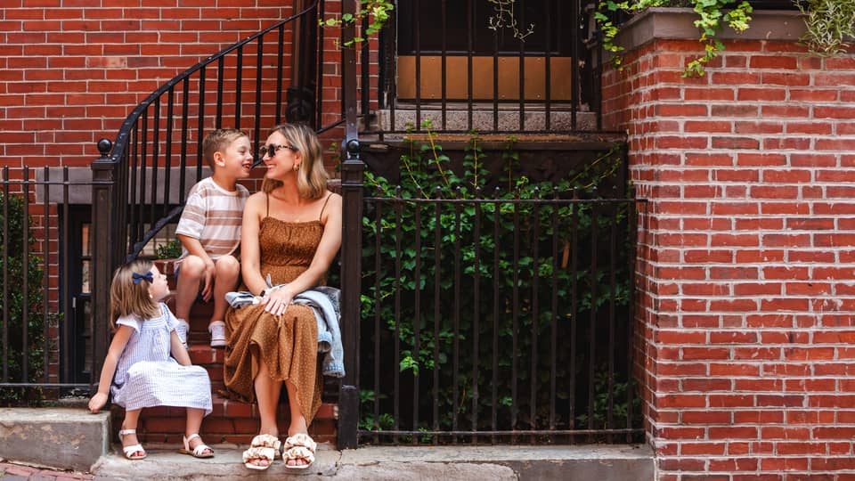 One guest sits on steps outdoors with two younger guests.