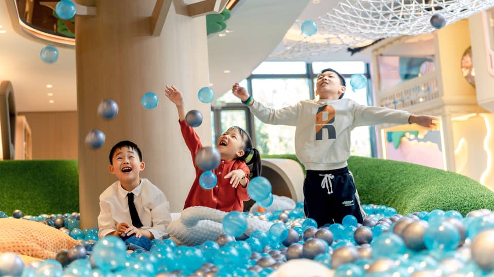 Three kids play in ball pit