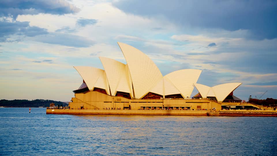 View of Sydney Opera House with its white, sailboat-like roof from harbour