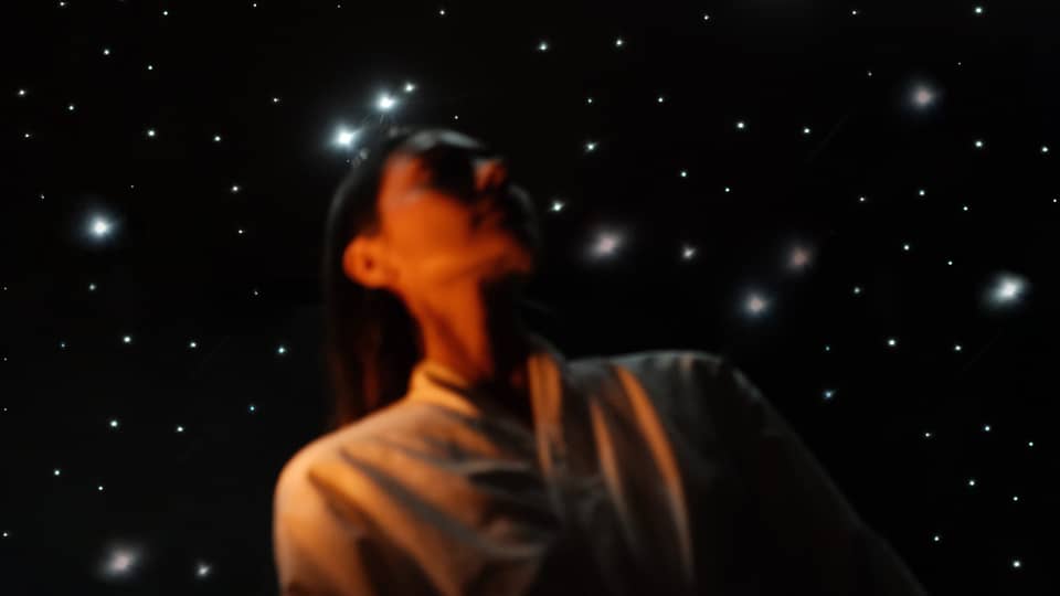 Guest wearing white spa robe stands in front of a ceiling lit to resemble a night sky filled with stars