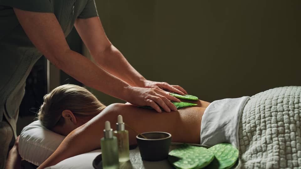 Guest laying on massage table with a blanket while getting a back massage.