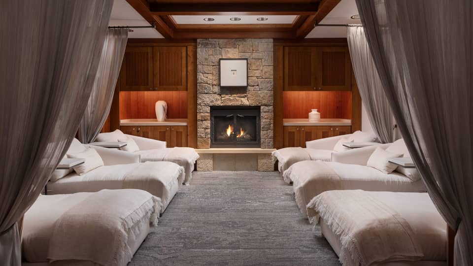 Lounge with spa beds, a fireplace and grey curtains.
