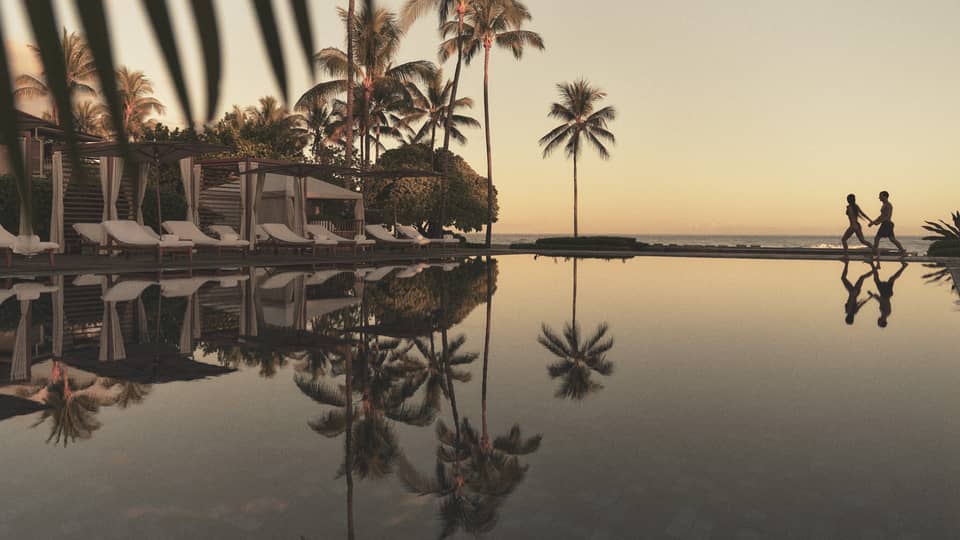A reflective pool at a tropical resort with beach in the distance