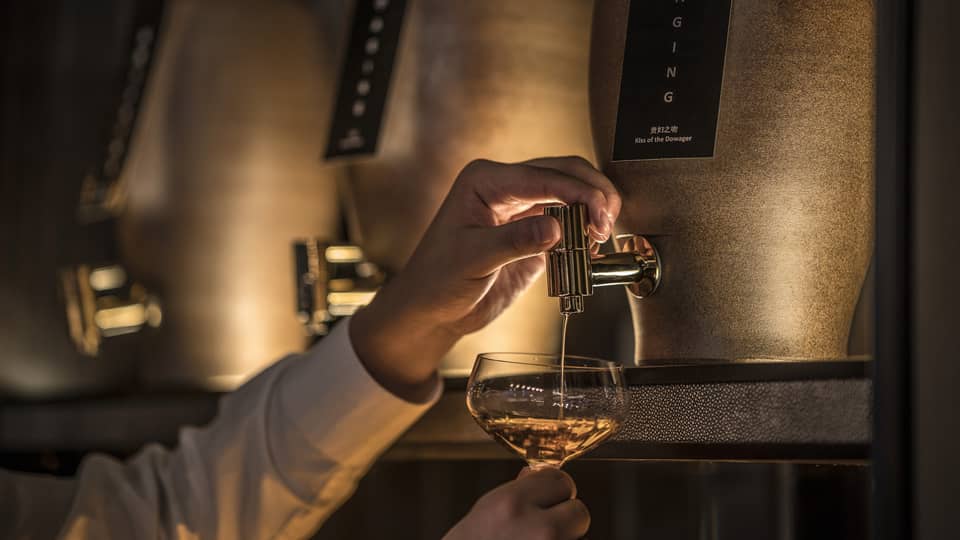 Close-up of bartender pouring liquor from tap into cocktail glass