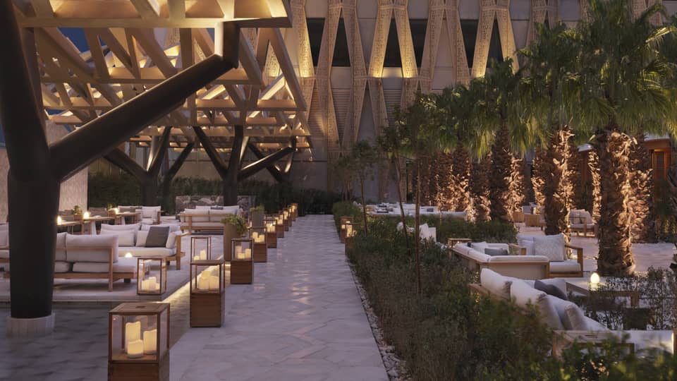 Illuminated outdoor patio sitting area with architectural designs on surround building.