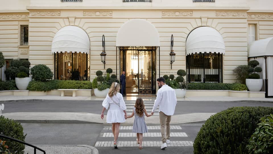 Family of three holding hands while walking toward the Grand-H�tel