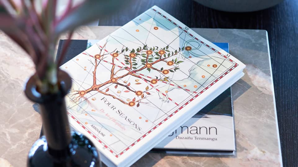 Four Seasons hotel book with an illustrated cover featuring a flowering tree on a table