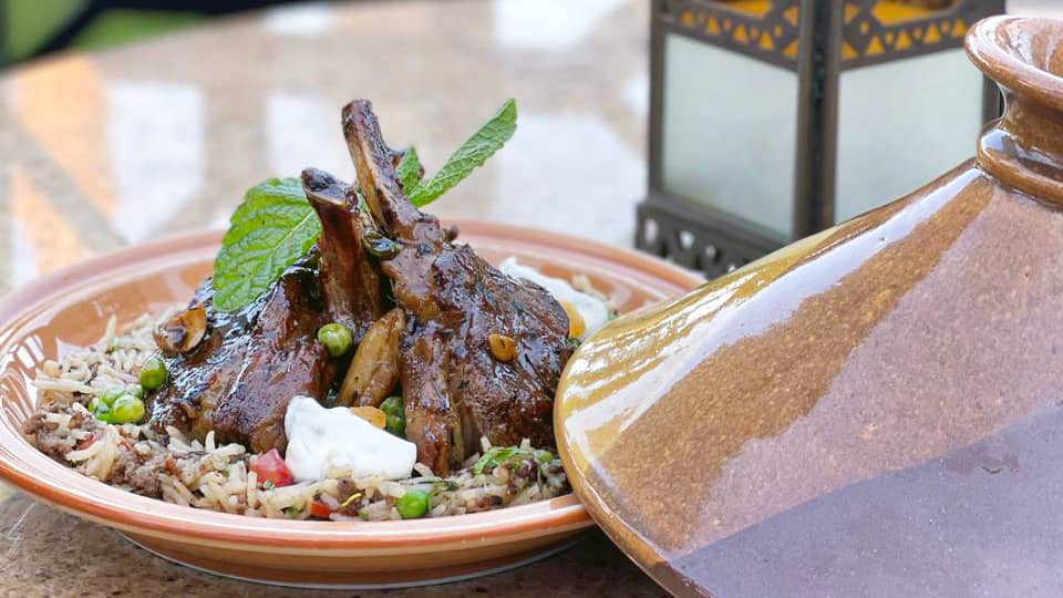 Lamb chops plated with tagine lid to the side and lantern on the table