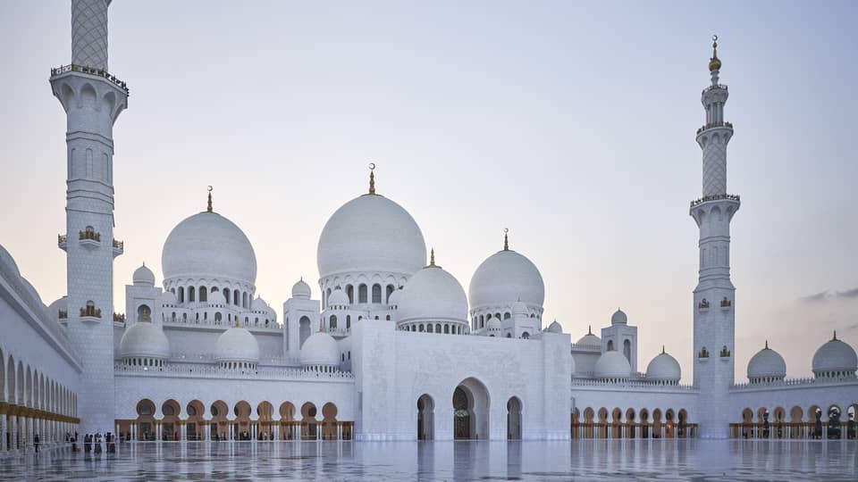 A large white mosque with two pillars made of marble.