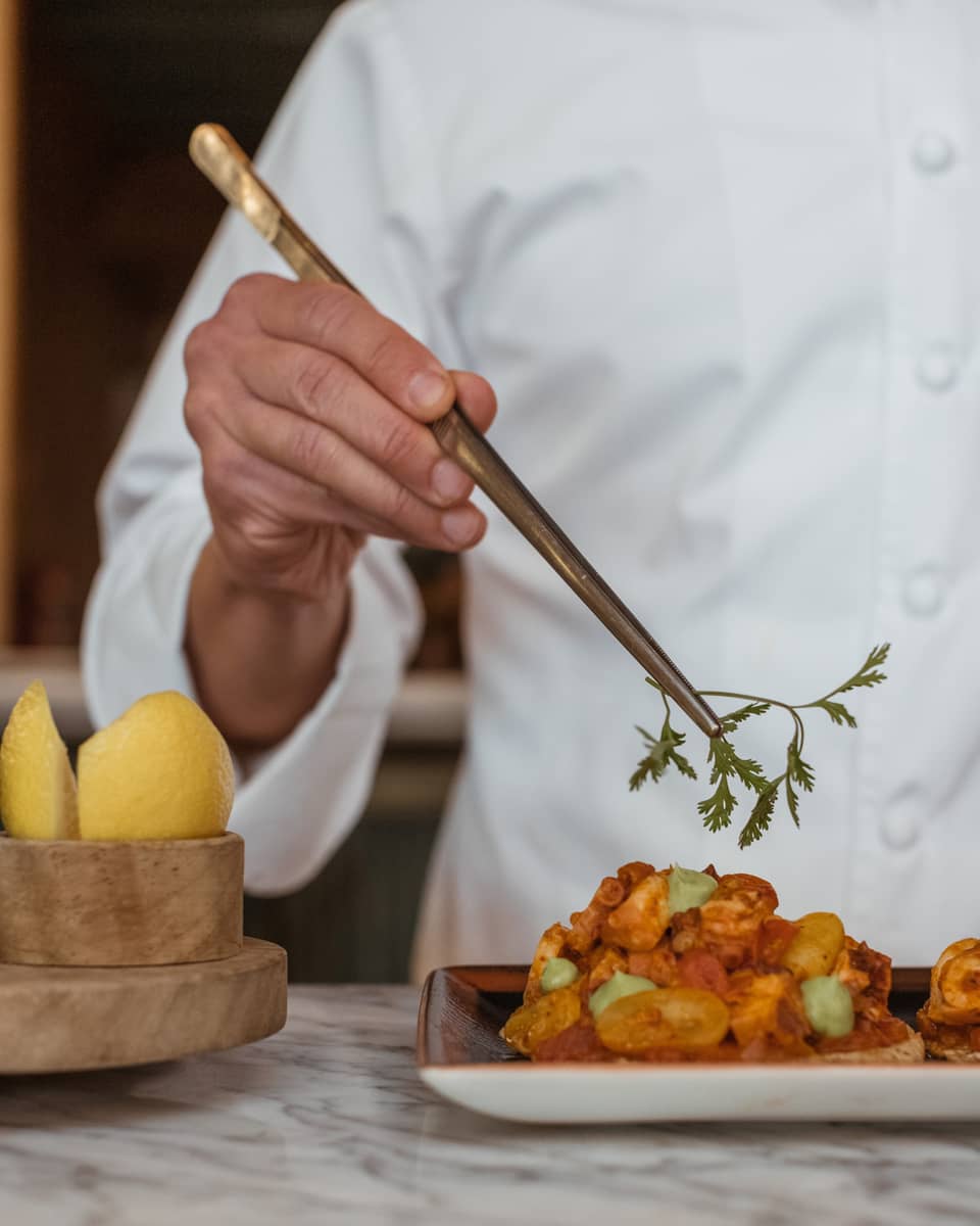 A chef picking up an herb with a utensil.