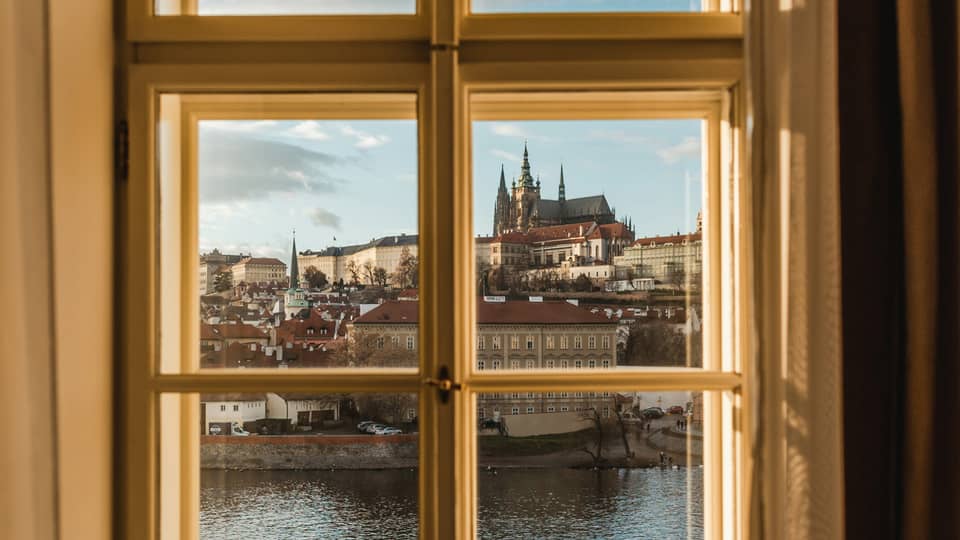 A view out a window, through windowpanes, of a cityscape on the other side of a body of water