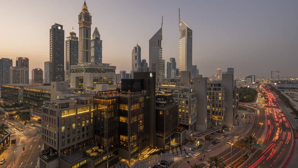 Aerial view of Dubai city skyline, road, lights around Four Seasons International Financial Centre hotel at sunset