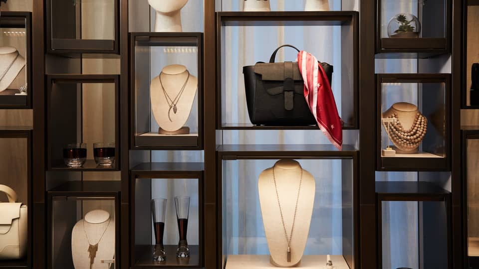 Boutique retail store shelf with designer necklaces, handbag, cocktail glasses 