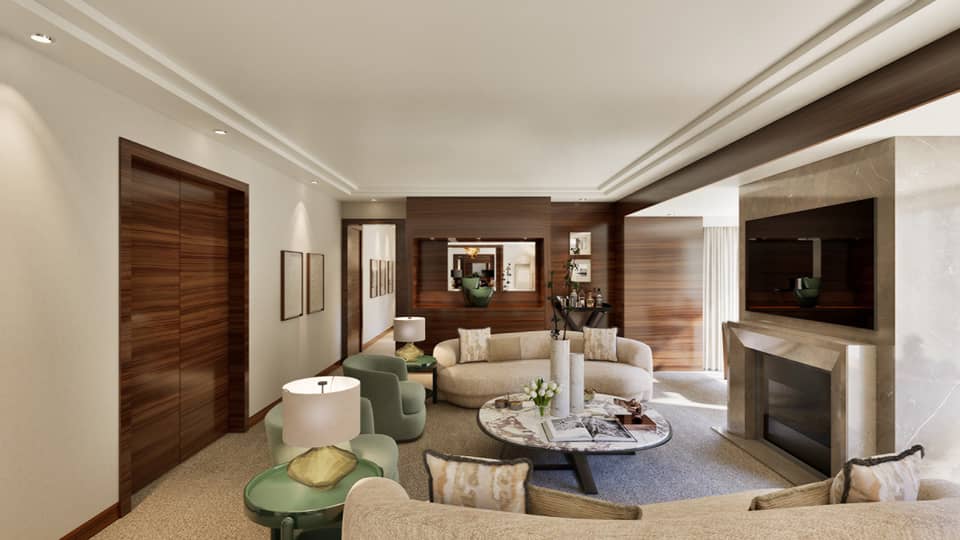 Luxury hotel suite living room featuring a cream-coloured curved sofa, large round coffee table, fireplace and TV