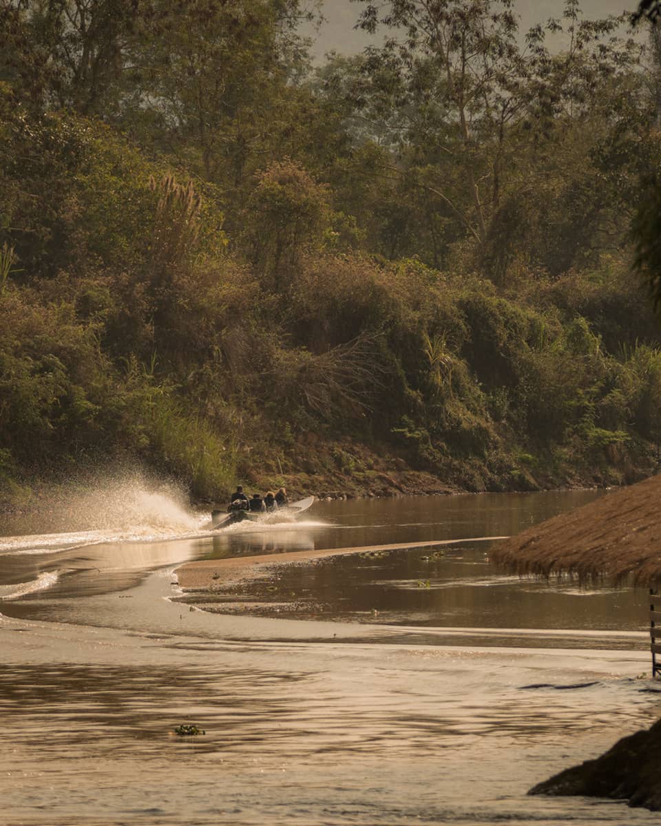 Longtail boat sprays water as it zips down the Ruak river