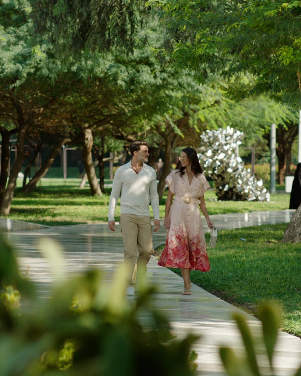 Couple walks along pathway surrounded by flora and fauna