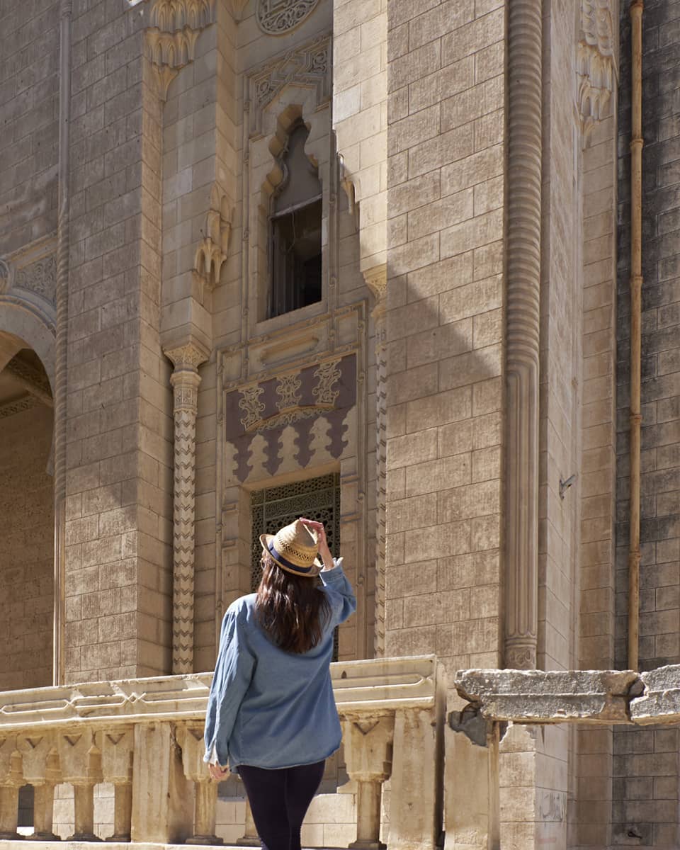 Woman looks up at historic palace exterior in Alexandria, Egypt 