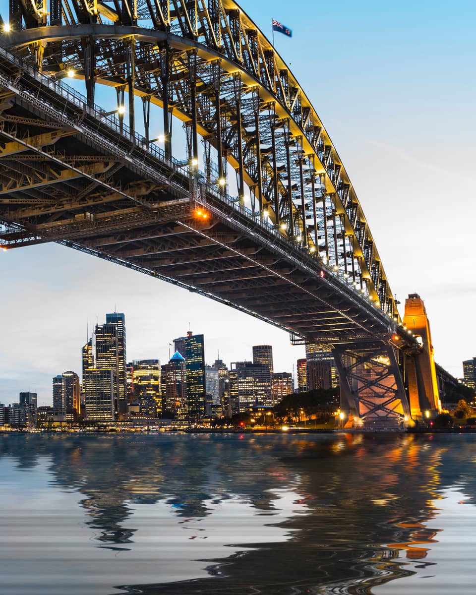 View from under bridge to Sydney waterfront skyline, lights at dusk