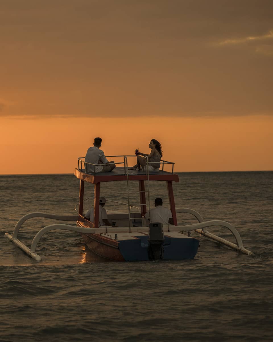 Sunset cruise boat on water under orange sky
