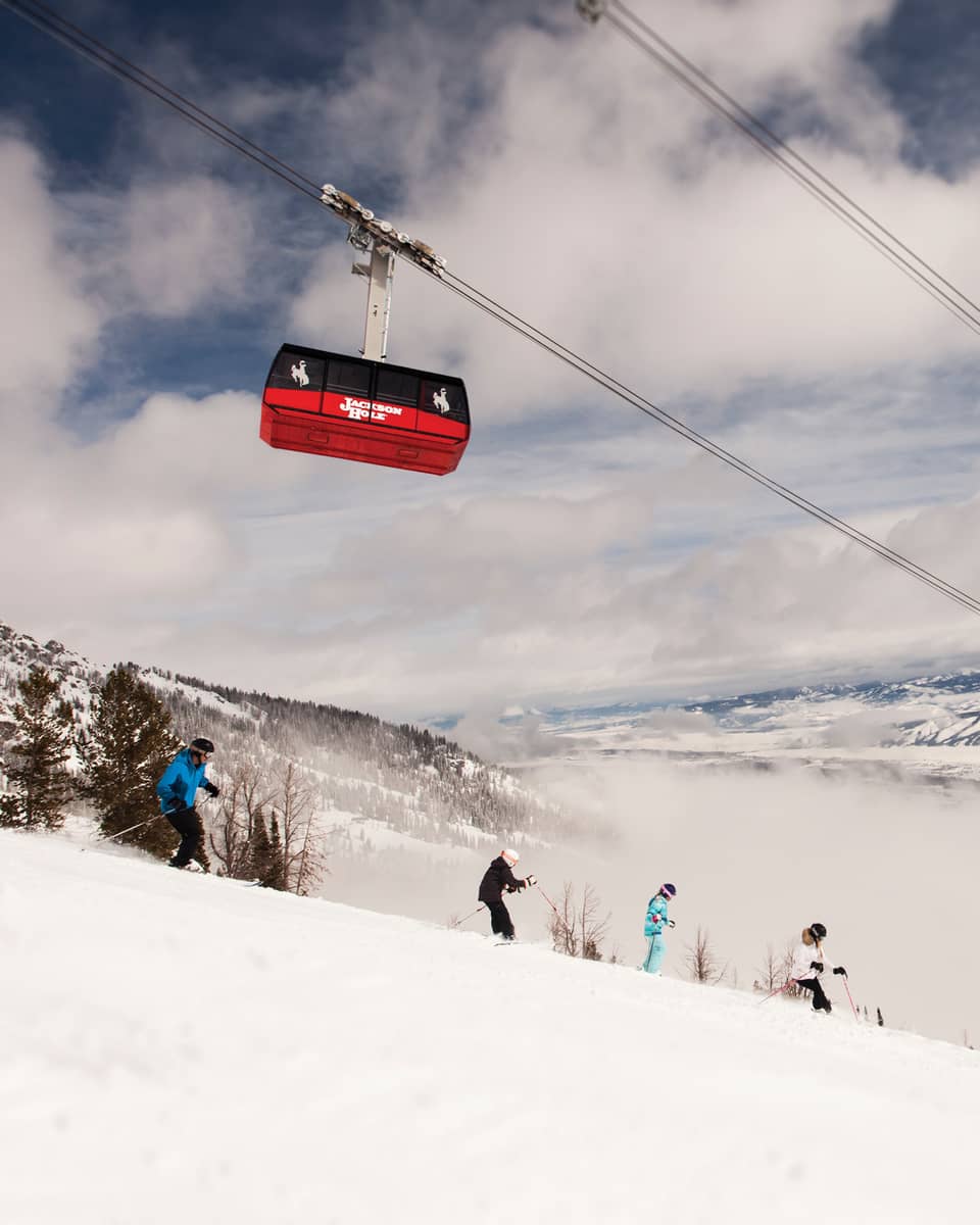 Red Sweetwater Gondola ski lift on wire above hikers on snowy mountain