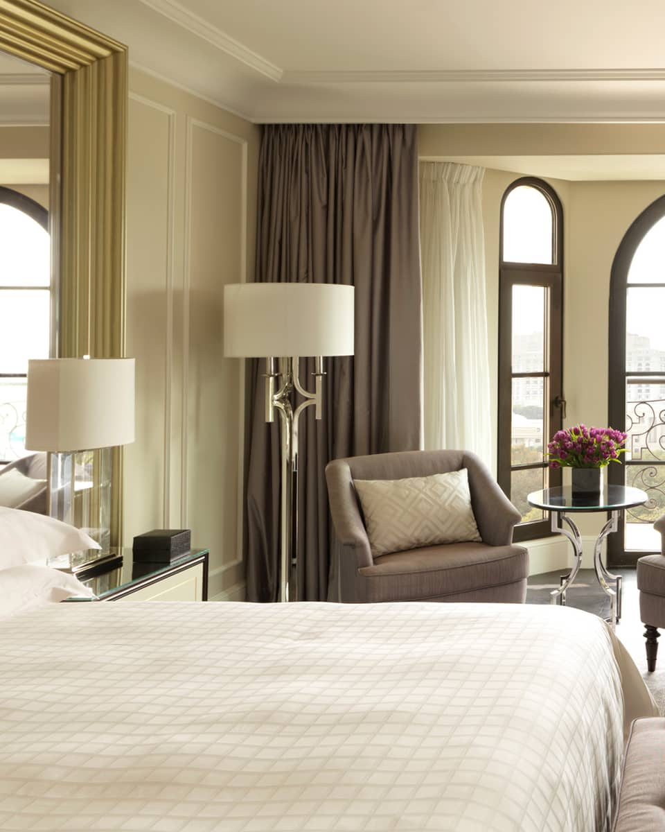 Sunny Deluxe Caspian Room hotel room with arched French doors, two armchairs, desk, bed