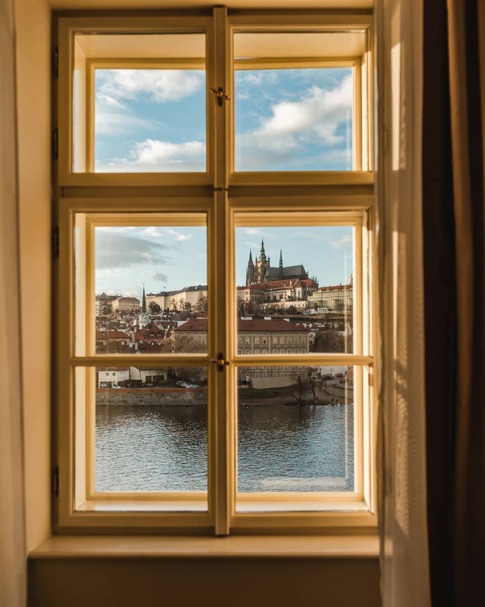 A view out a window, through windowpanes, of a cityscape on the other side of a body of water