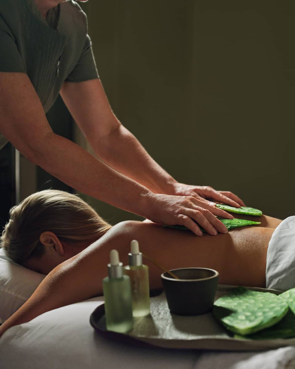 Guest laying on massage table with a blanket while getting a back massage.