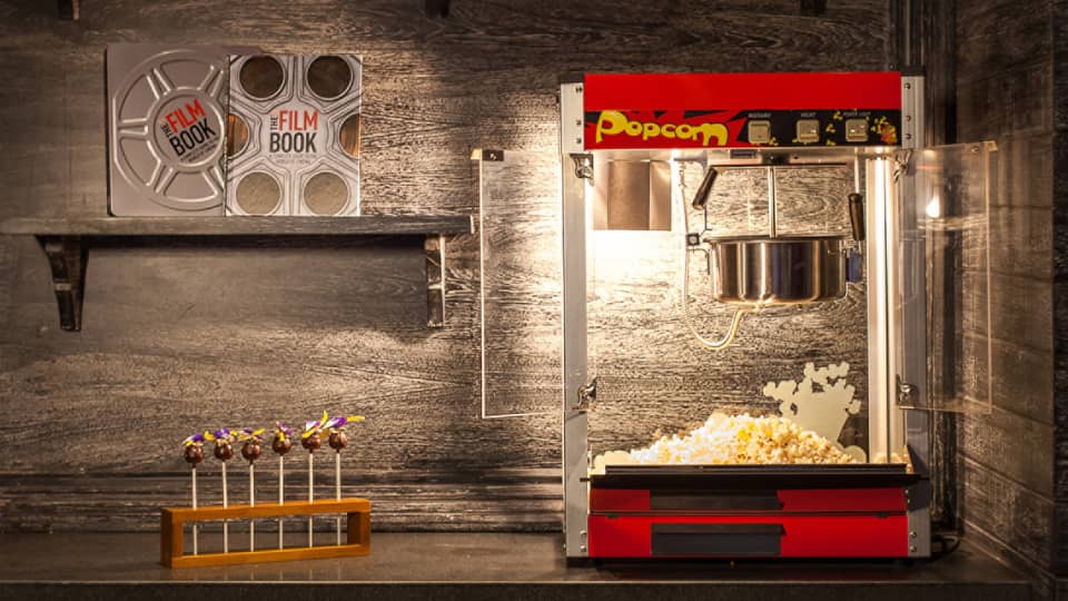 Popcorn machine, candy and film books on shelf in dark room