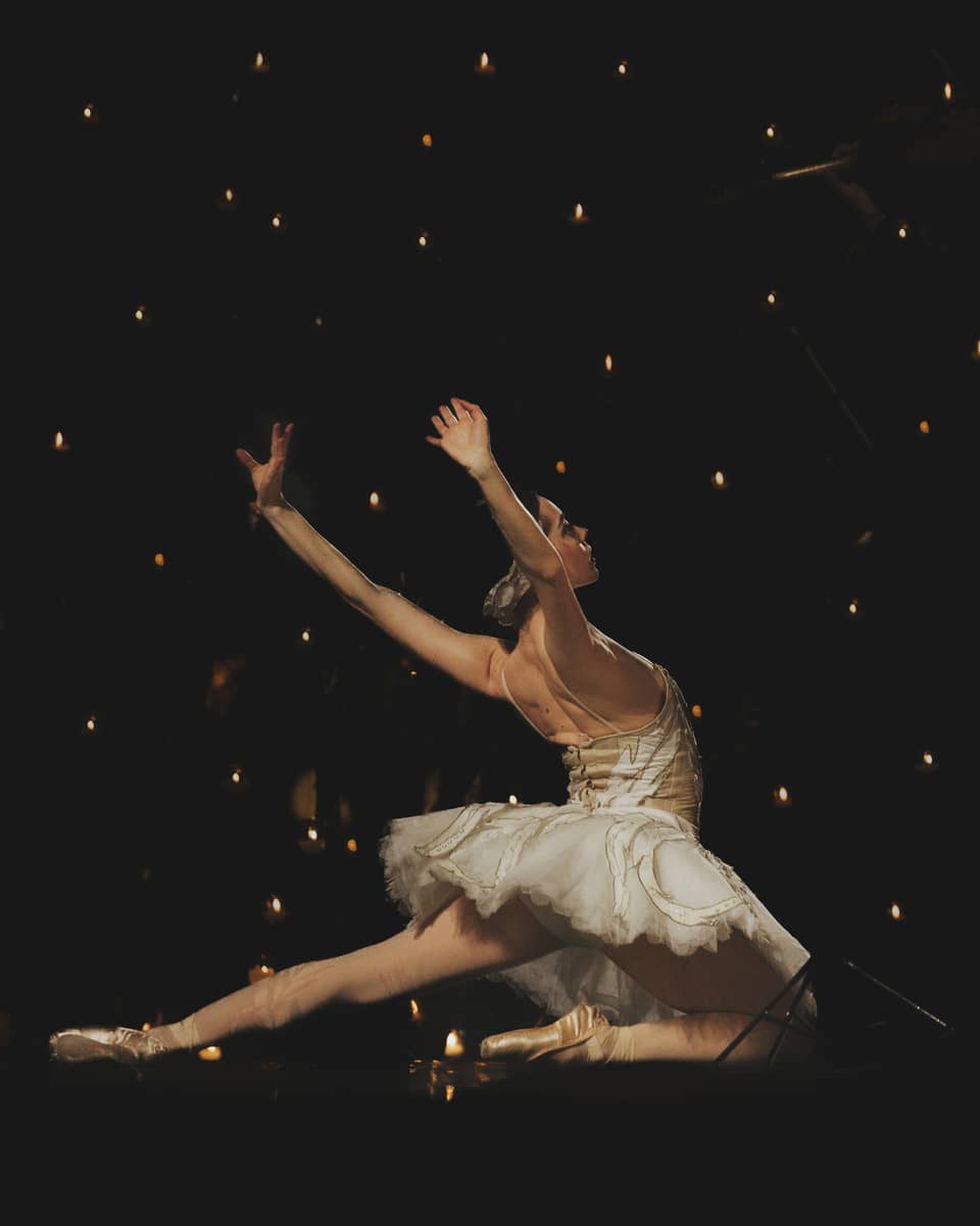 A ballerina dancing in front of a dark background