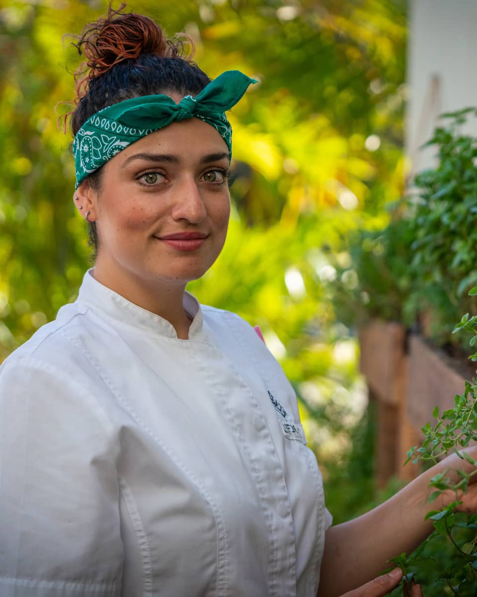 A female chef in a green bandana looking at herbs.