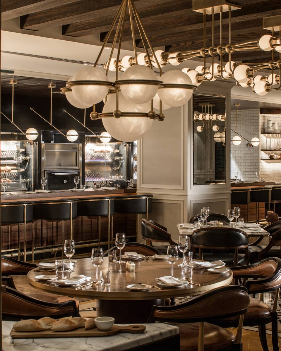 The interior of a dining outlet with many hanging lights, various tables, and a bar.