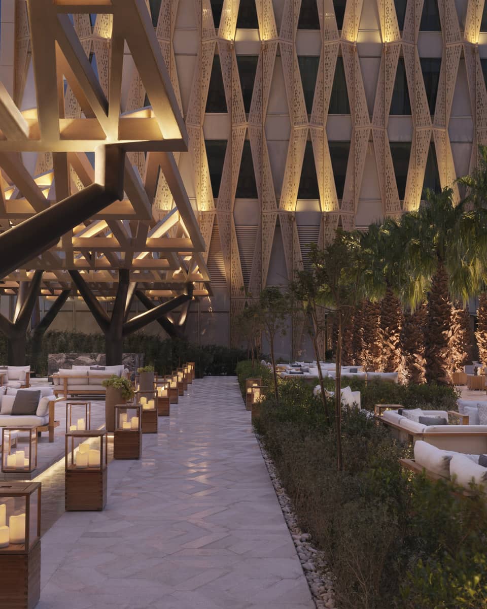 Illuminated outdoor patio sitting area with architectural designs on surround building.