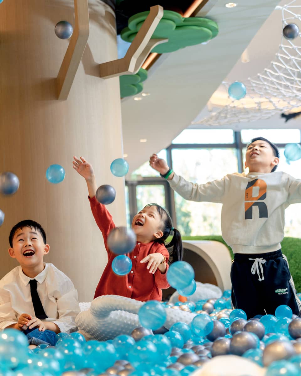 Three kids play in ball pit