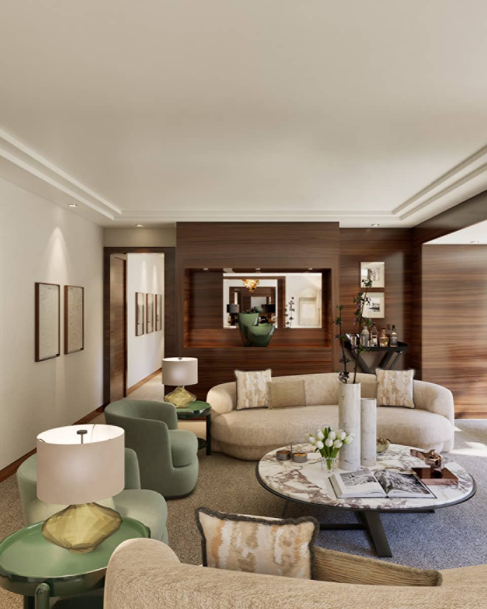 Luxury hotel suite living room featuring a cream-coloured curved sofa, large round coffee table, fireplace and TV