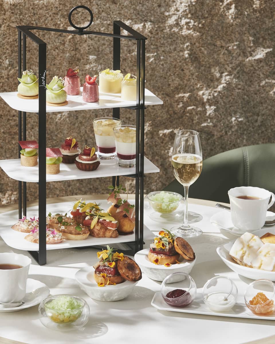 Afternoon Tea set up with three-tiered display of sweet and savoury foods, two glasses of champagne and two glasses of tea