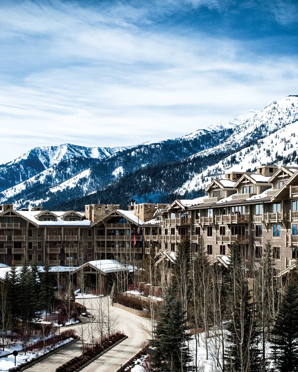 the exterior of the hotel is covered in snow and surrounded by snow capped mountains 