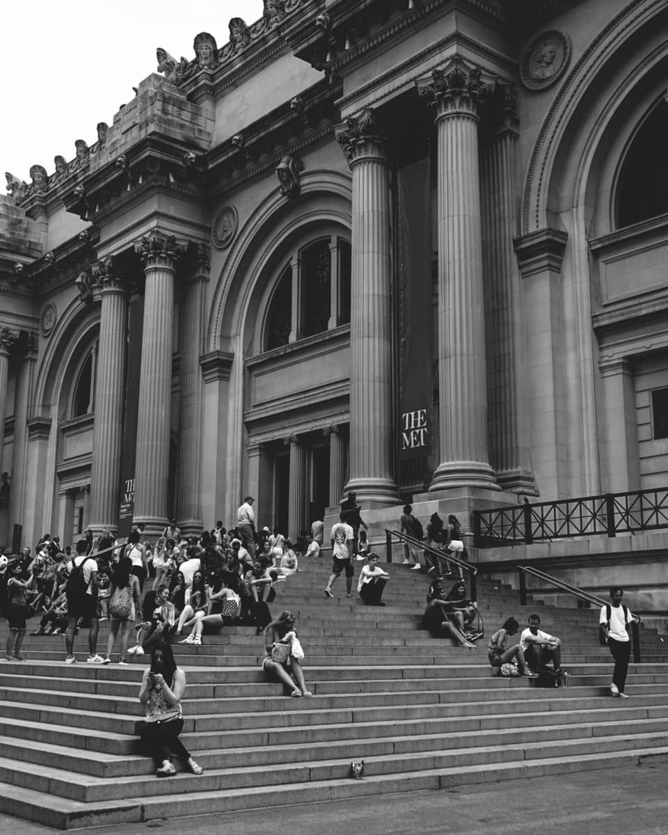 People walking up the steps to a large building with columns.