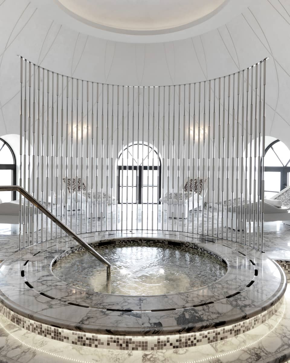 Round spa tub with black-and-white marble and tiles in middle of white dome room