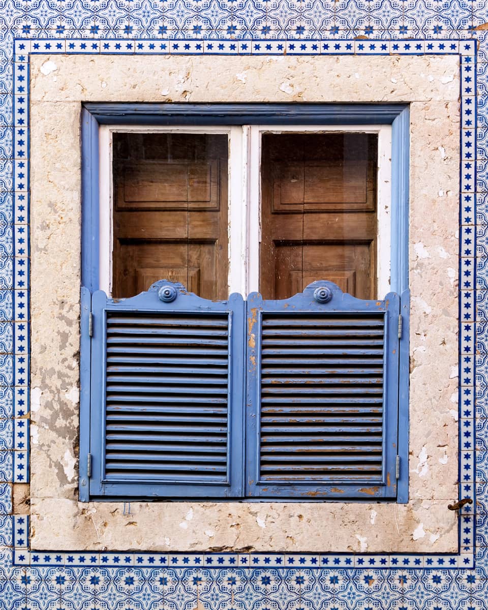 A blue wall and window covered in blue and brown doors.