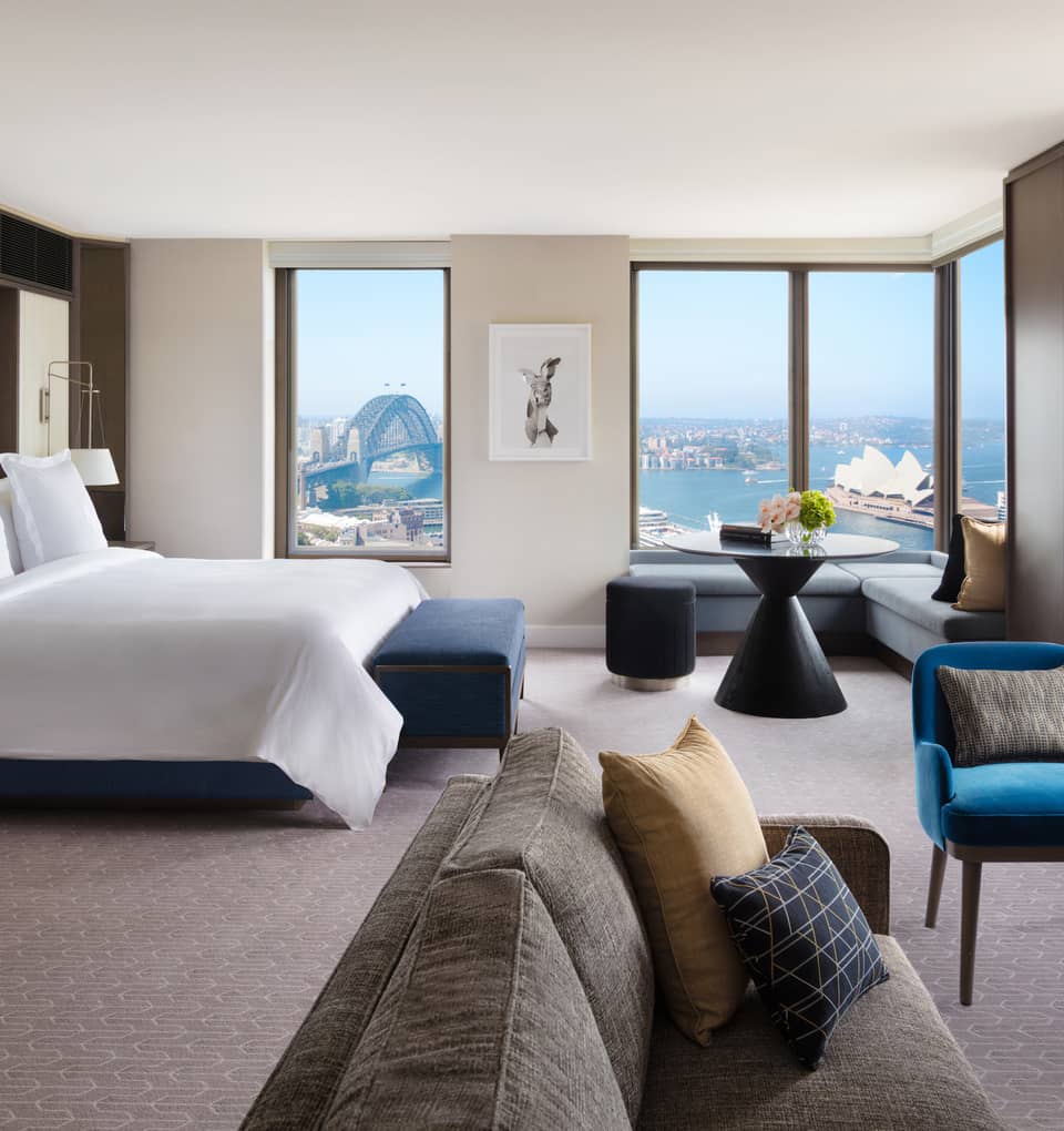A cozy bedroom with subtle bursts of colourful decor, overlooking the iconic Sydney Harbour